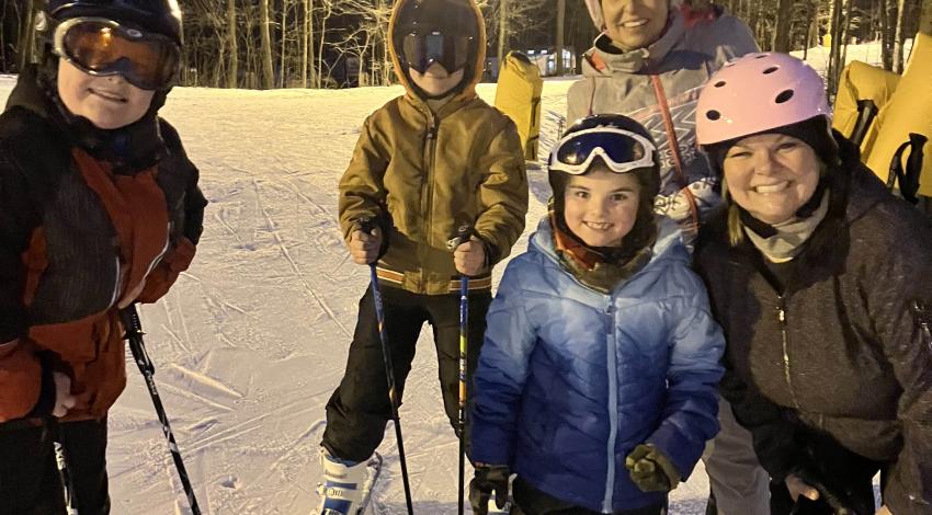 a woman and four kids on snow skis