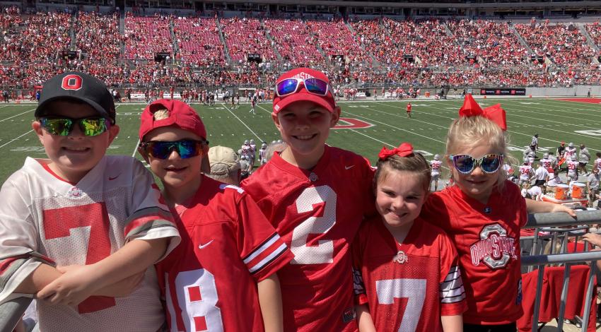 five kids in Ohio state gear in front of football field