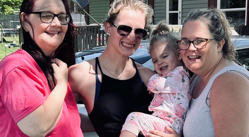 three women and a baby smiling outside