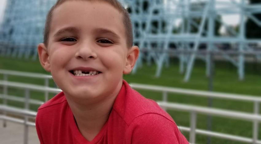 boy standing in front of blue roller coaster