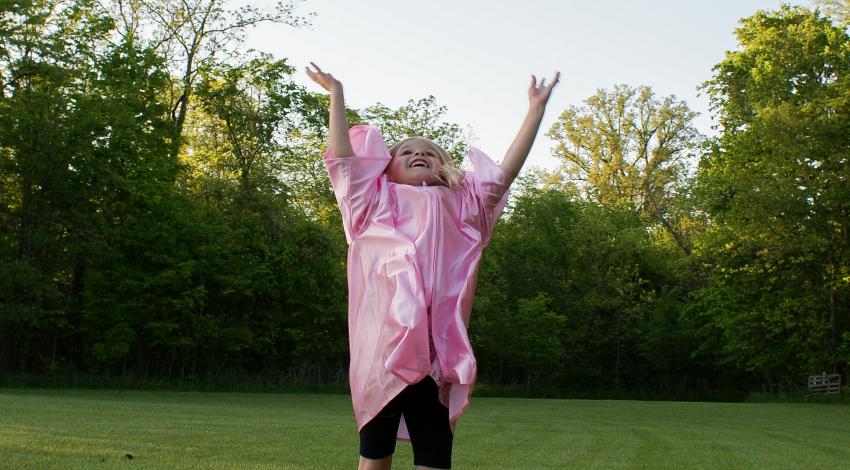 little girl tossing pink graduation cap in the air