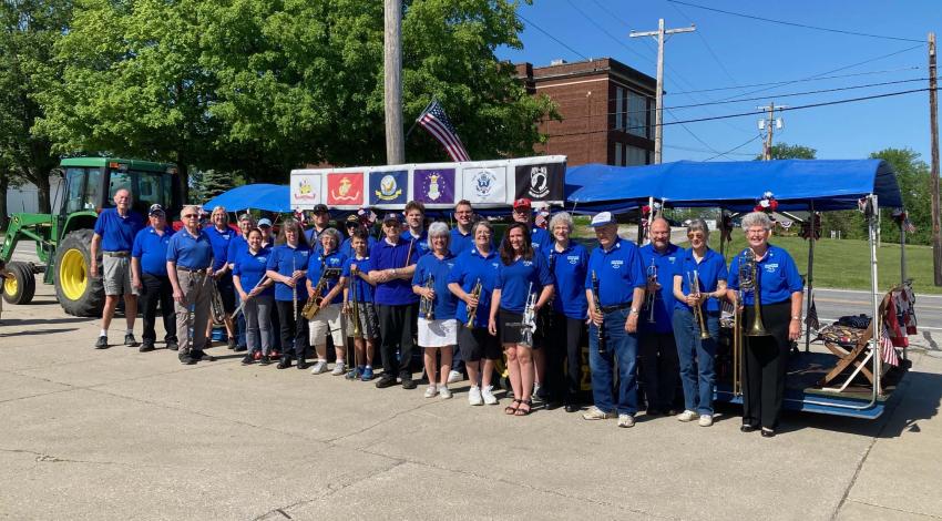 group of people outdoors, in matching shirts and holding instruments