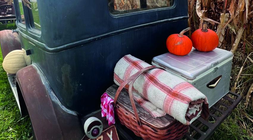 picnic basket and blanket on back of old-fashioned car