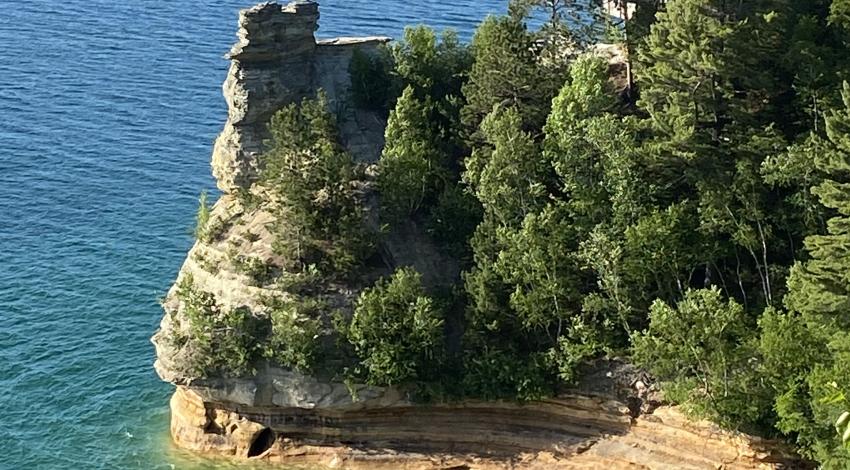 tree-covered rock juts into blue lake waters