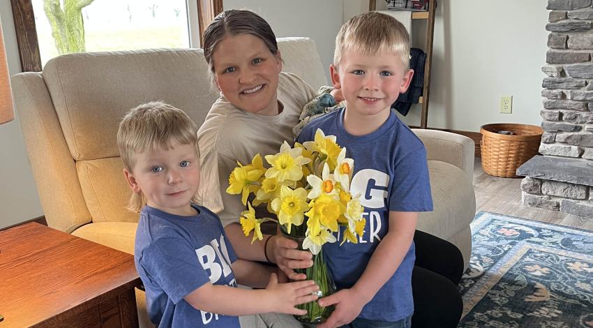 two little boys giving flowers to a woman