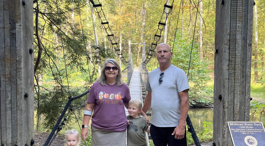 man, woman, and children on swinging bridge