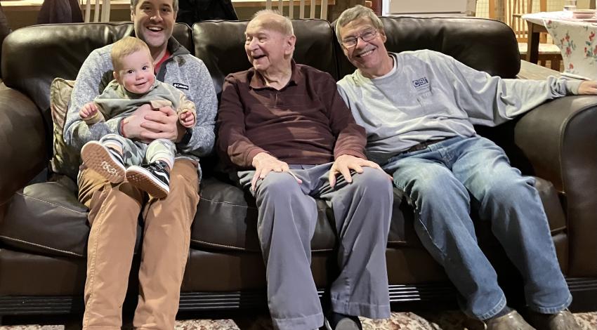 three men and a little boy on a couch