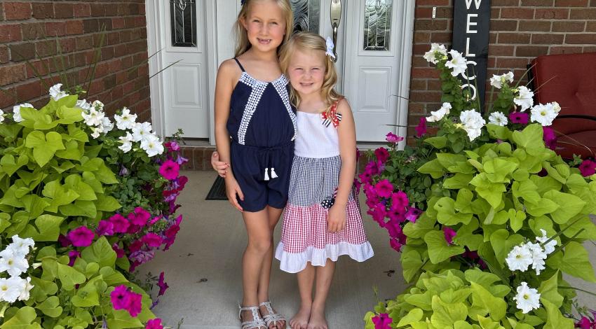 two girls on porch with white and pink flowers