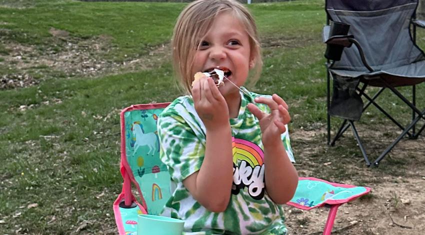 smiling girl bites into a s'more