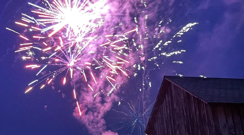Barn silhouette in front of night sky with fireworks