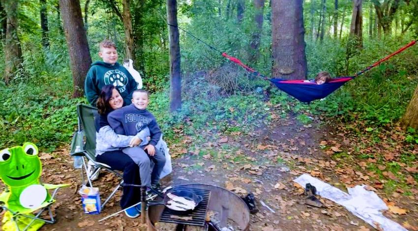 woman and three children by campfire