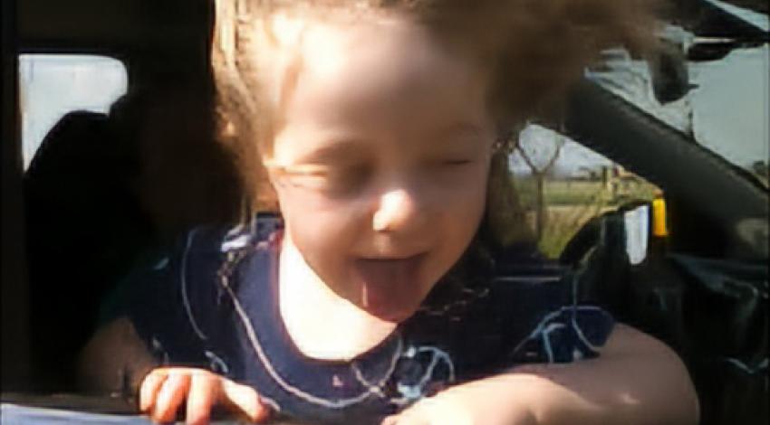 little girl with hair blowing in car window
