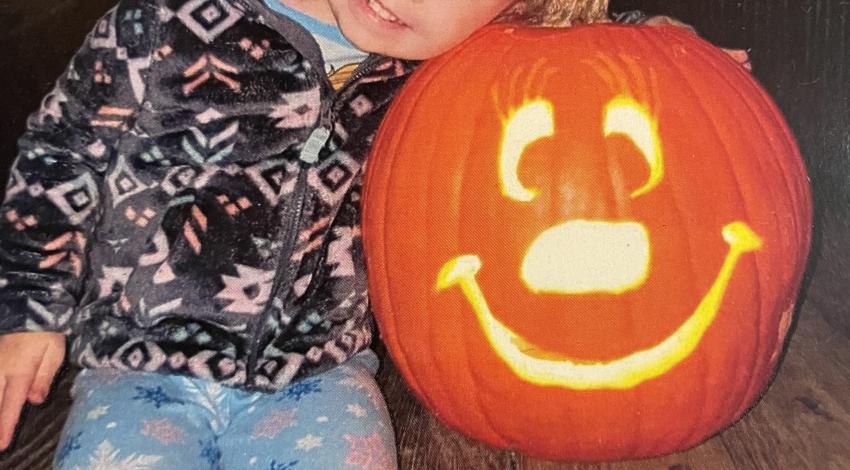 little girl hugging smiling jack-o-lantern