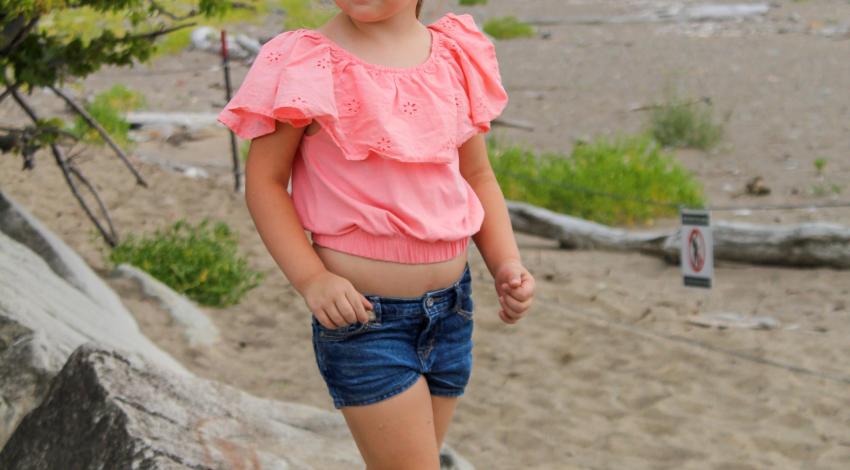 little girl on rocks by sandy beach