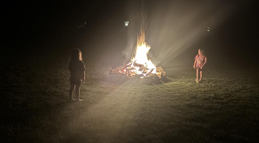 two girls standing in glow of campfire