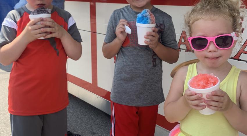 Three children hold snow cones.