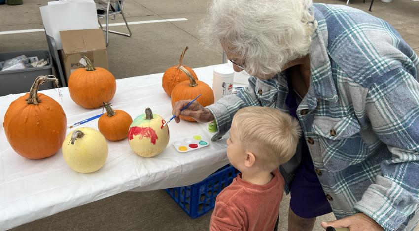 little boy and woman painting pumpkins