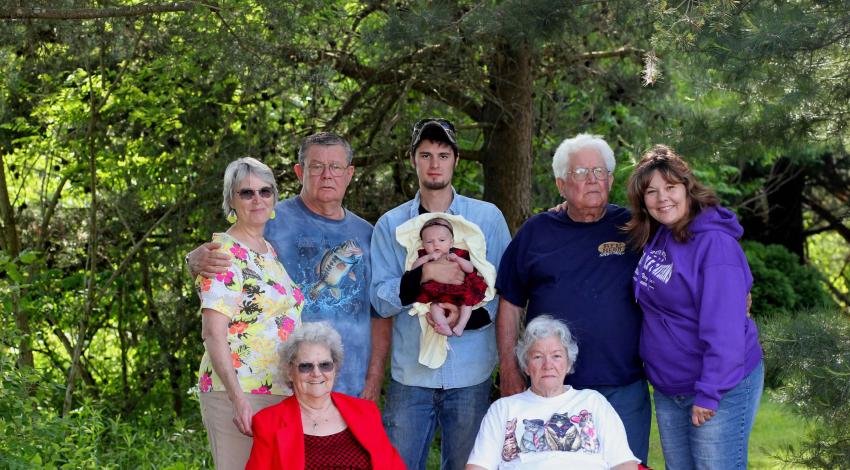 several generations pose in front of trees