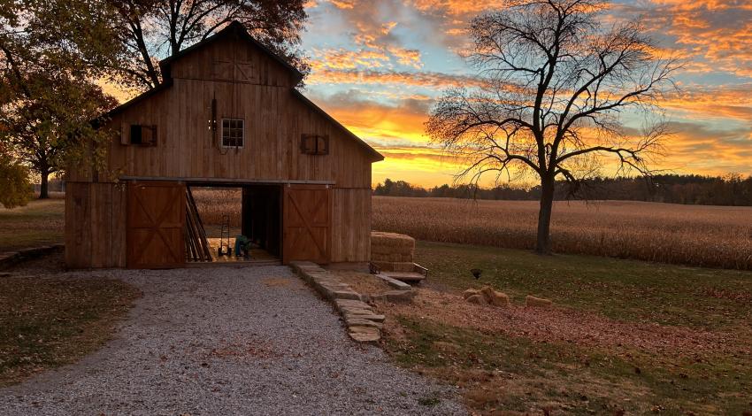 Brown wood barn with sunset in background