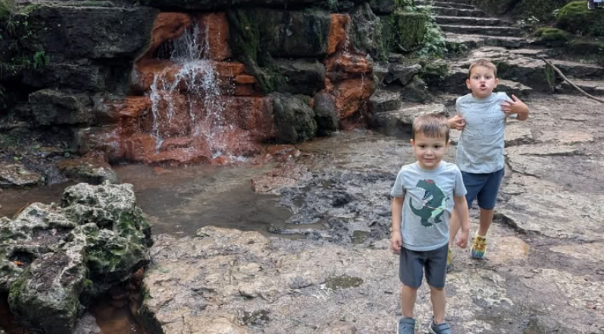two kids in front of small waterfall