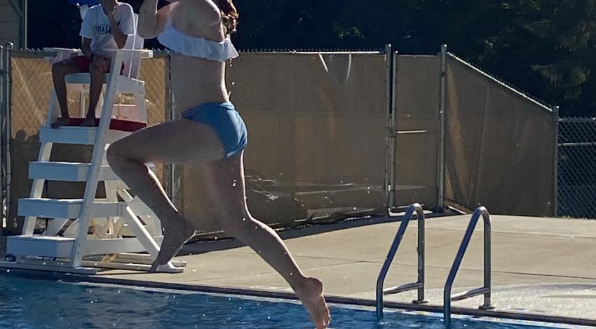 girl jumps off diving board into pool