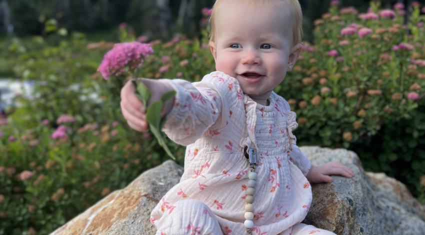 baby holding pink flower