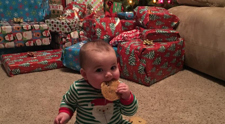 baby eating cookie in front of Christmas tree