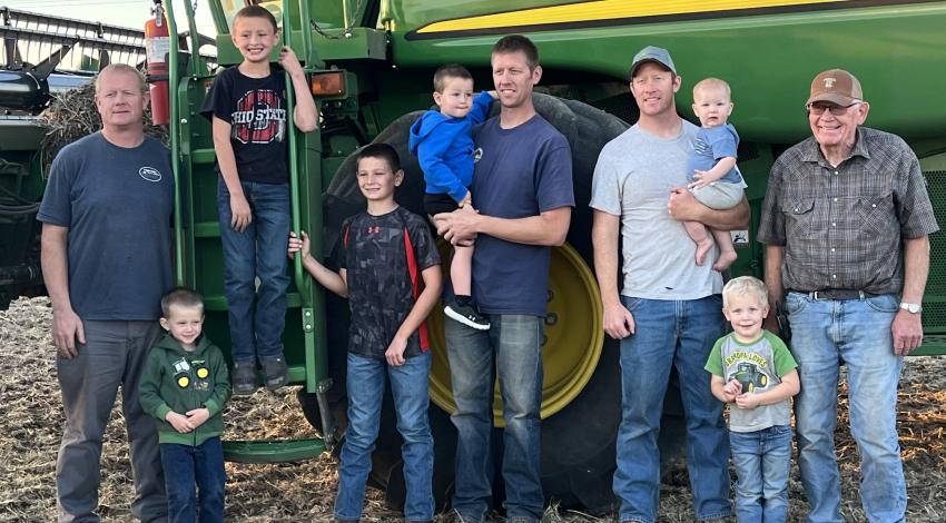 men and boys in front of green farm machinery