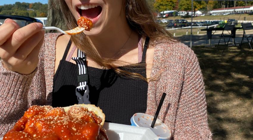 Young woman taking a bite of sauce-covered pasta