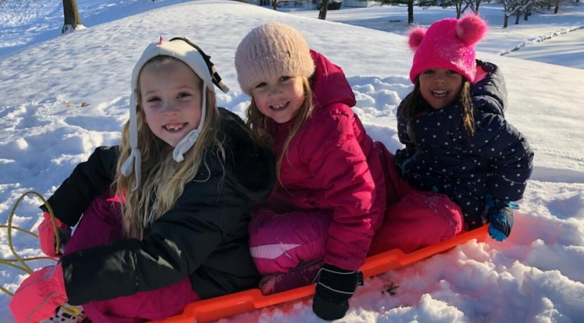 three kids on sled in snow
