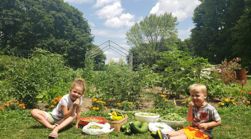 A boy and a girl sit in a sunny garden