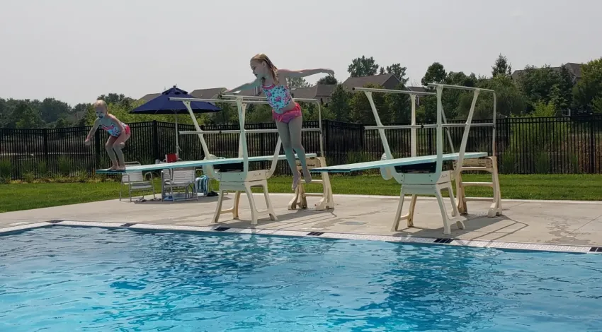 two girls jump off diving boards