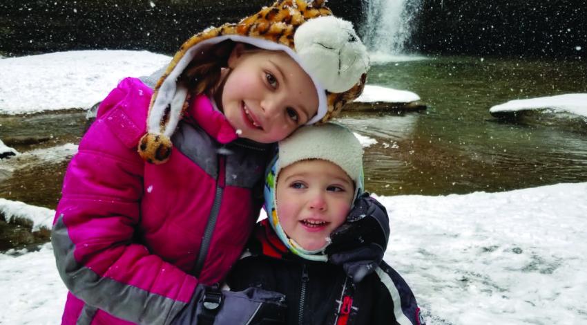 two kids in front of waterfall in winter