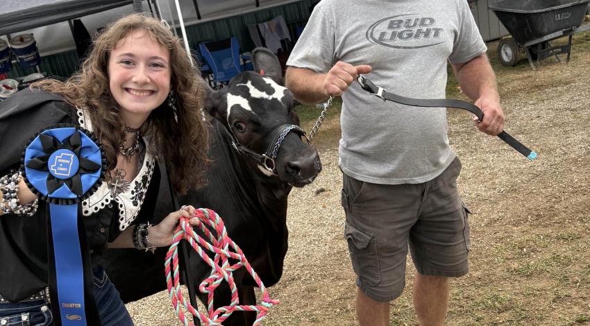 girl holding ribbon and man with cow