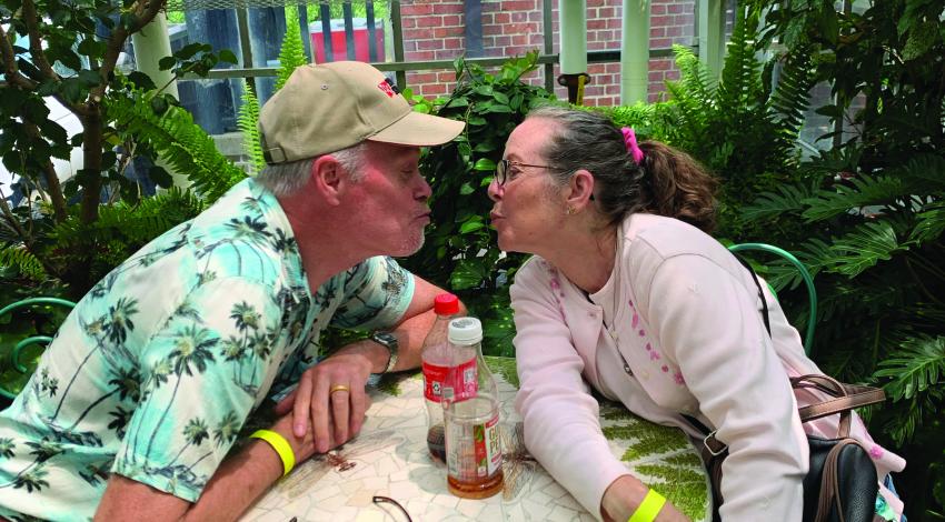 couple leaning in over table for a kiss