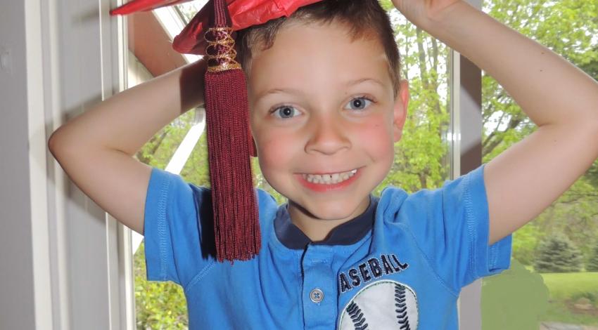 little boy in red graduation cap