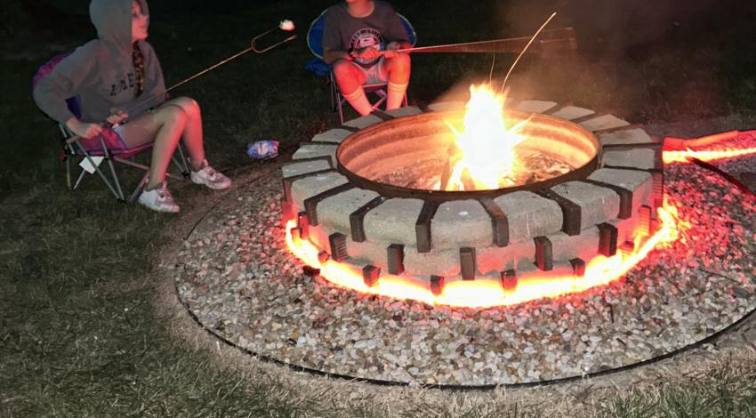 two children roasting marshmallows over fire pit