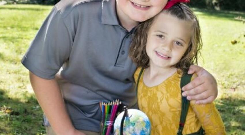 boy and little girl kneeling by desk with books and globe