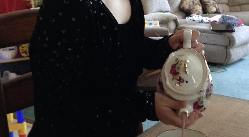 girl carefully pours tea from china teapot into teacup