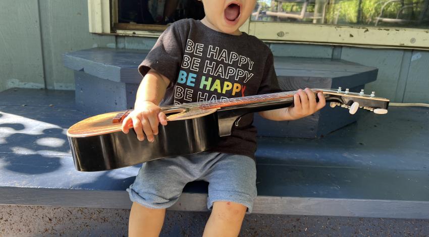 little bo on edge of porch, holding guitar and singing
