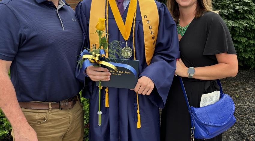 young man in blue graduation gown, between parents