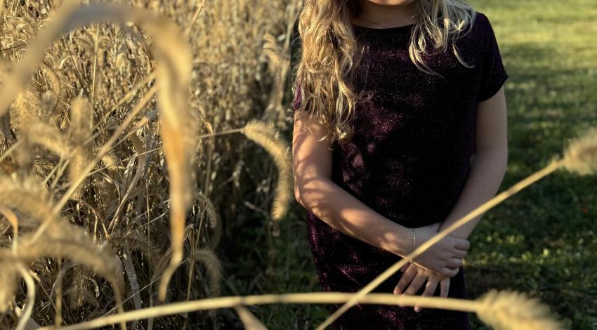 girl by cornfield with trees in background