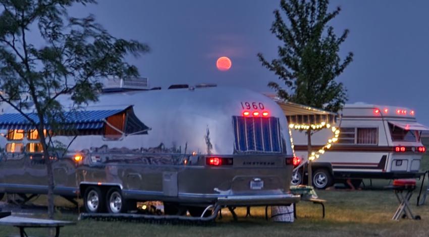 Shiny camper with pink moon in the distance.