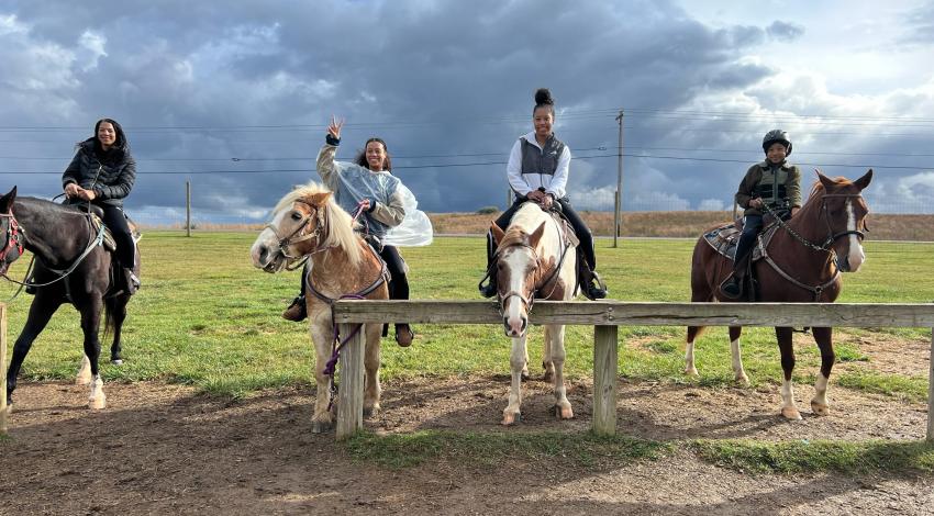 four people on horseback in front of cloudy skies