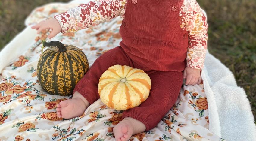 baby girl on blanket with pumpkins