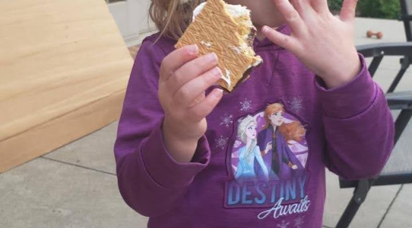 little girl licking s'more off her fingers