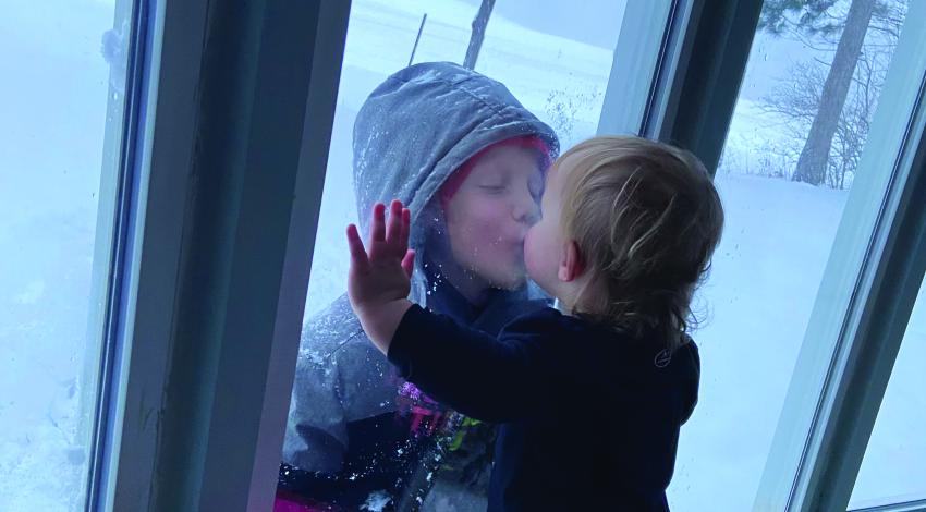 children kissing on either side of window