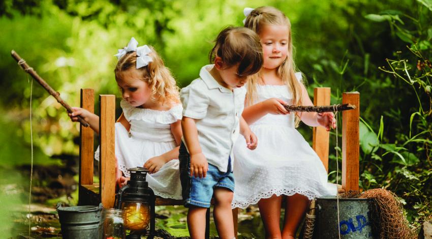 two little girls and a little boy on a bench