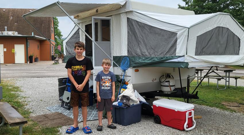two boys standing in front of pop-up camper