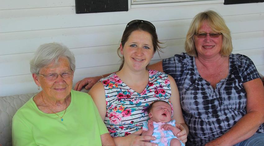 three women and a baby seated on a porch